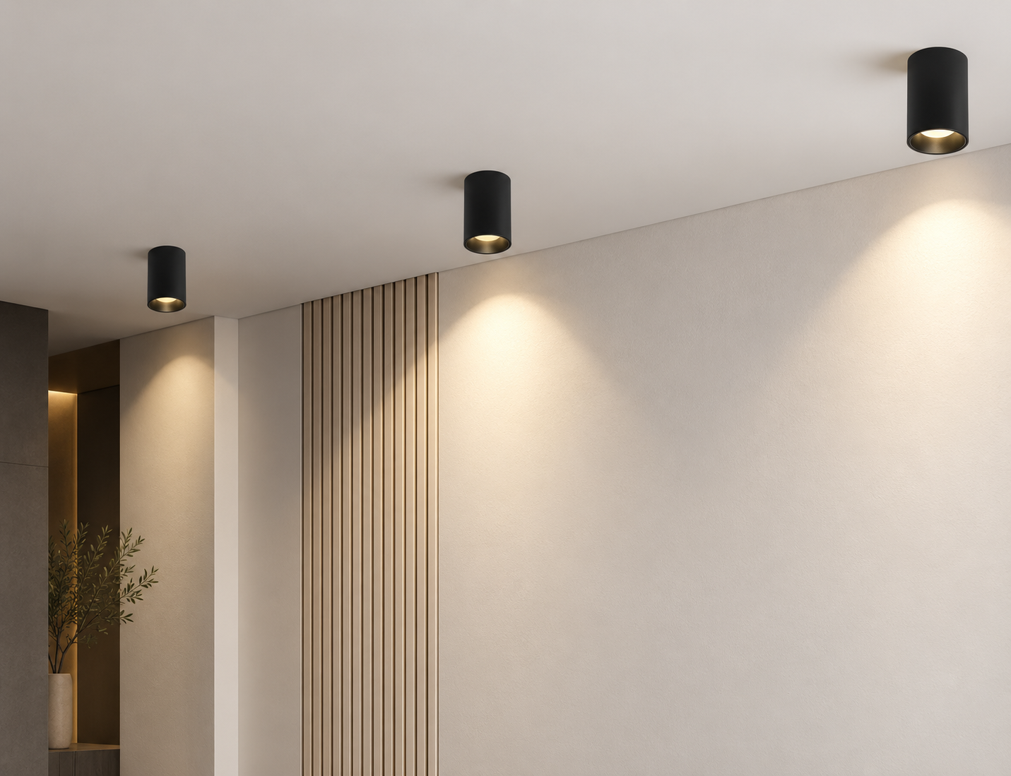 Ba đèn spotlight ốp trần màu đen tạo các vùng sáng ấm trên tường trong không gian nội thất hiện đại